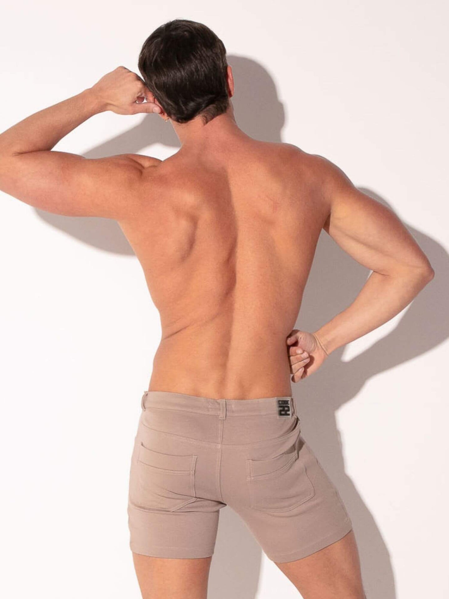 Man wearing beige cotton shorts against a white background