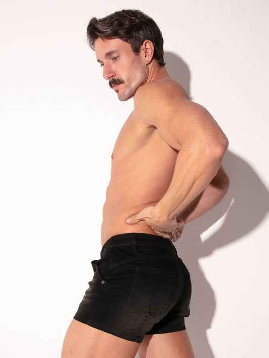 Man wearing black denim shorts against a white background