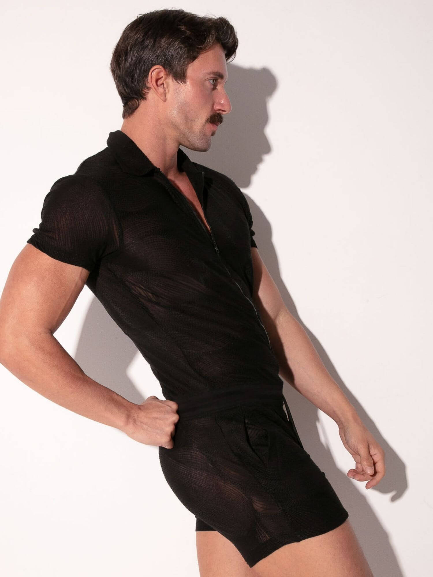 Man wearing a sheer black romper against a white background
