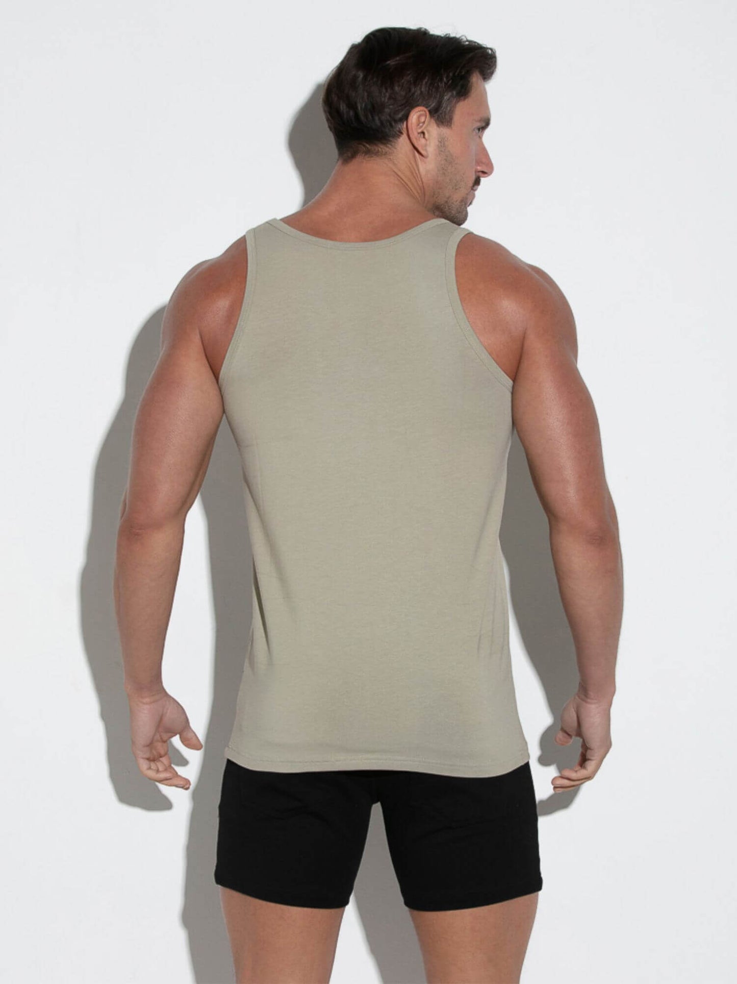 Man wearing a beige tank top and black shorts against a white background