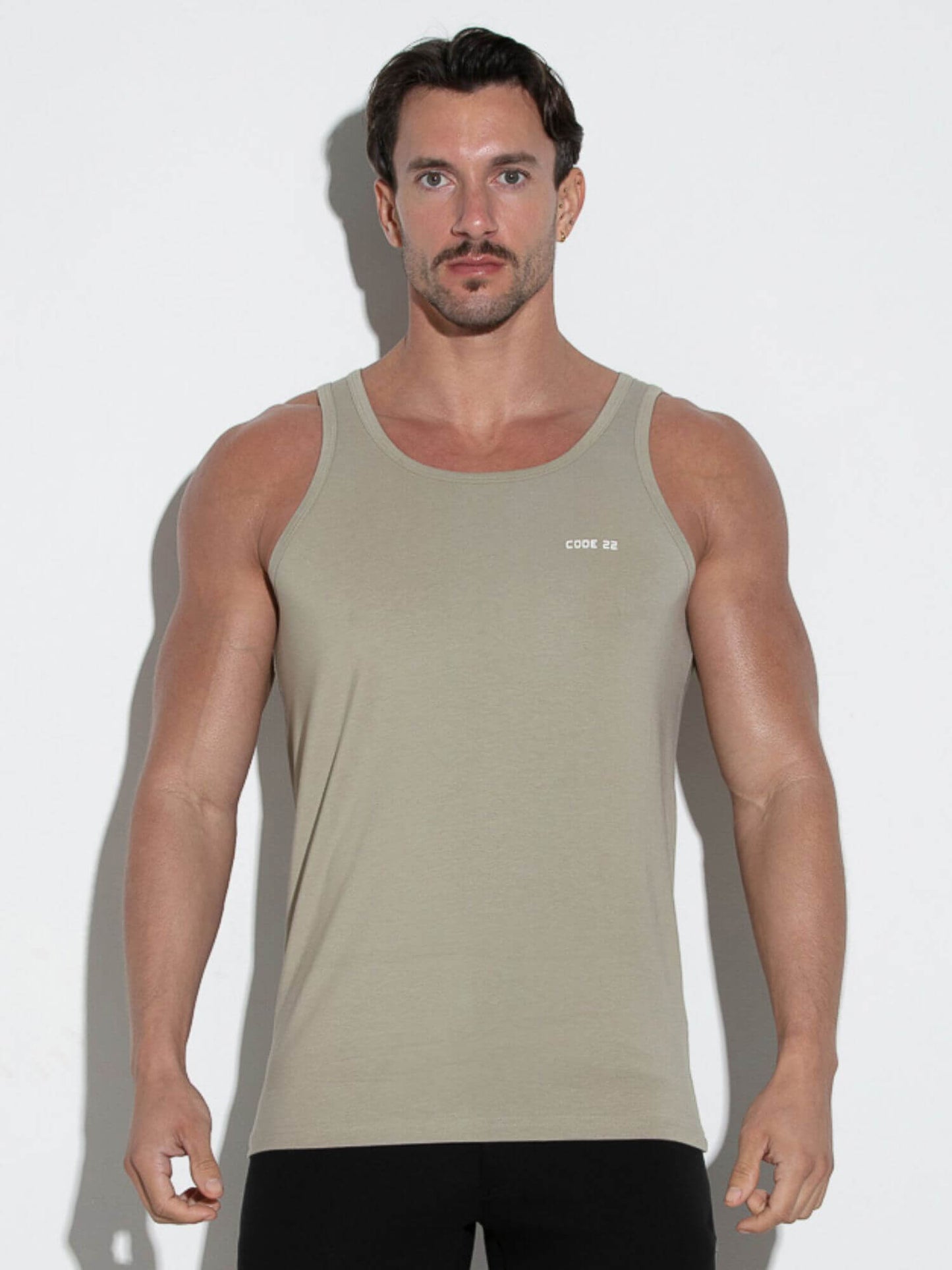 Man wearing a beige tank top against a white background