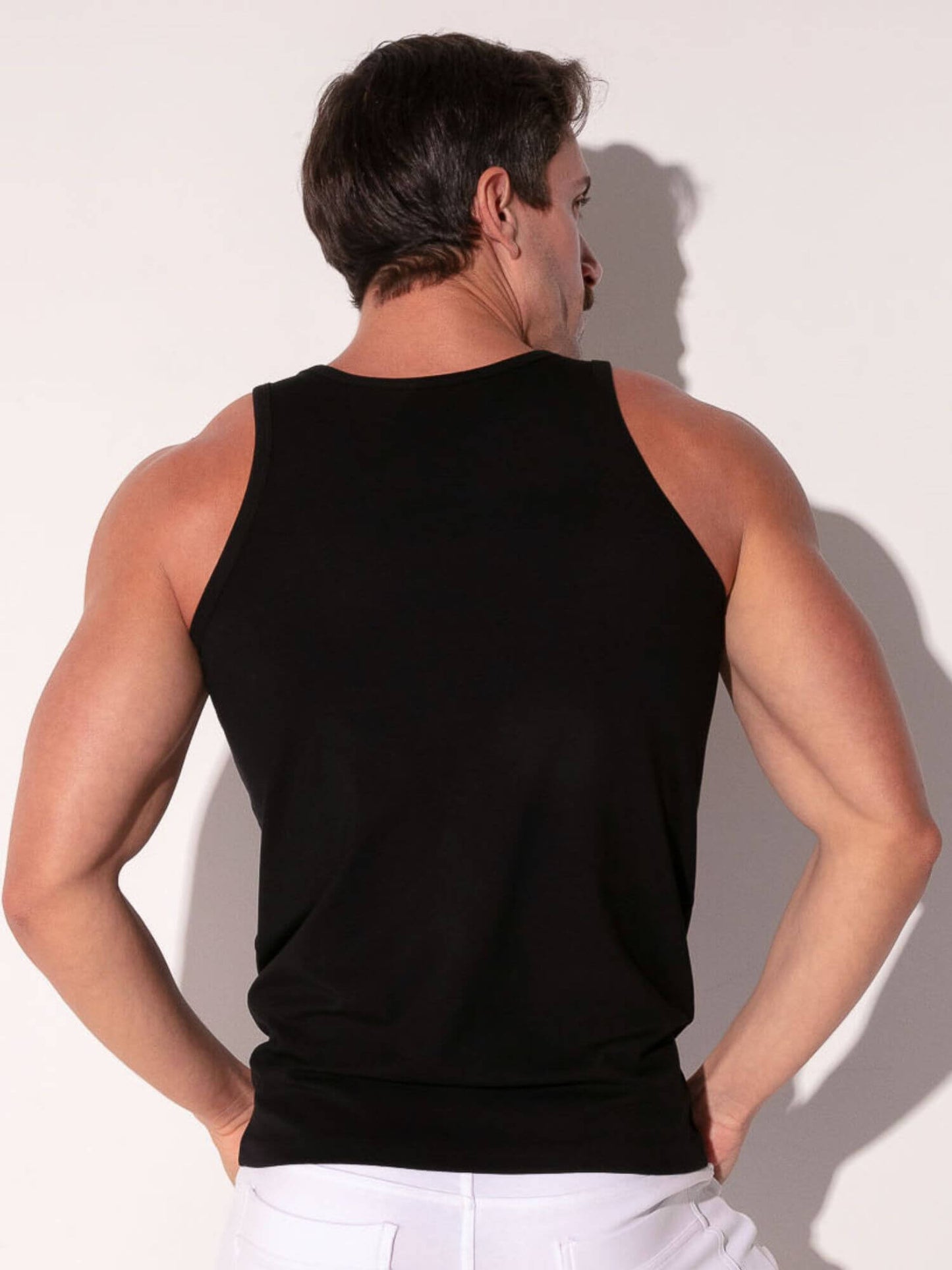 Man wearing a black tank top against a white background