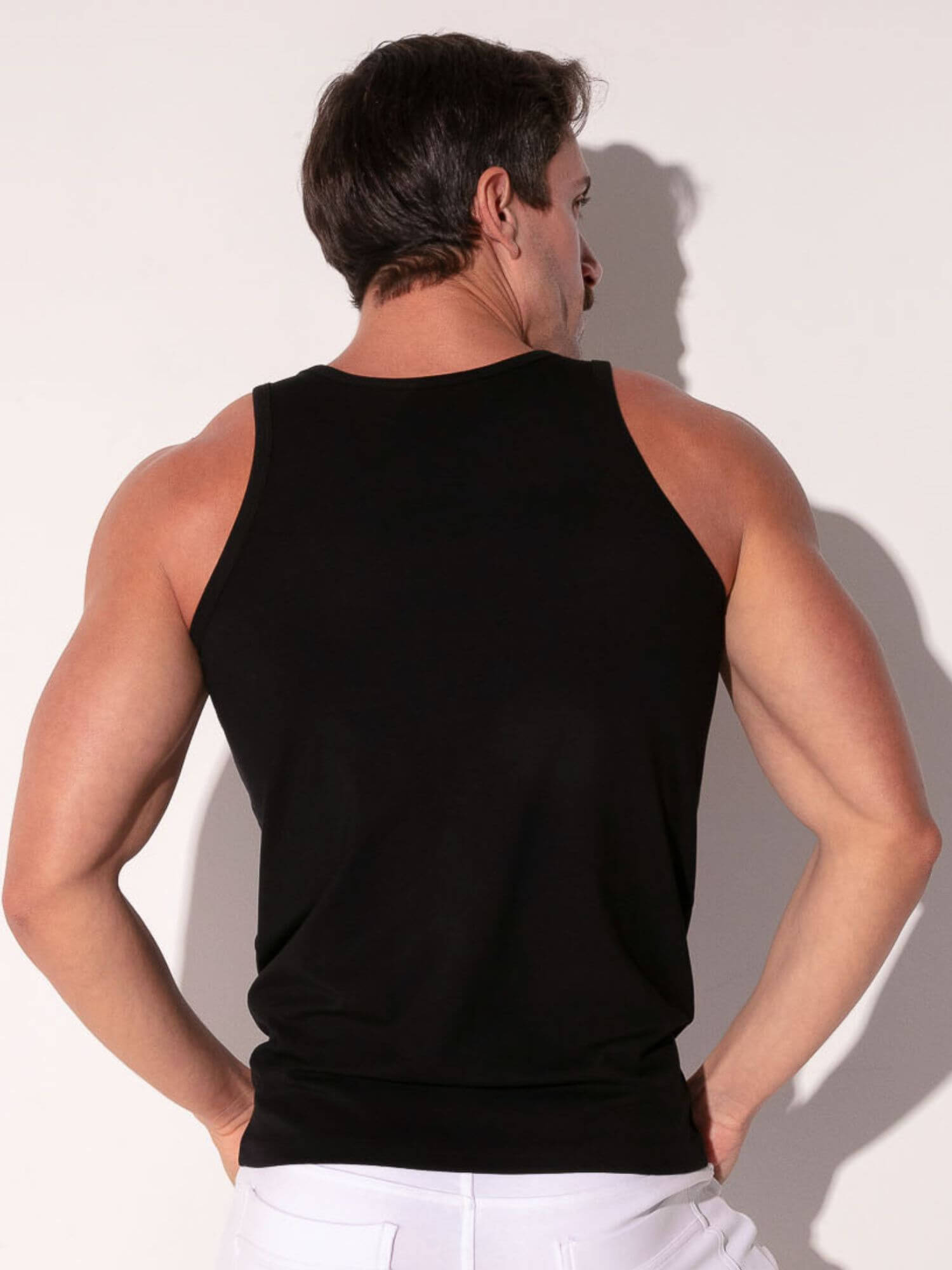 Man wearing a black tank top against a white background
