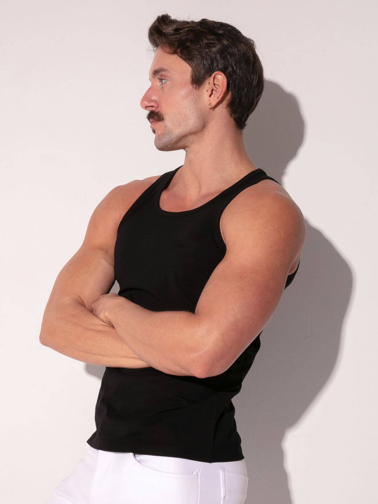 Man wearing a black tank top against a white background