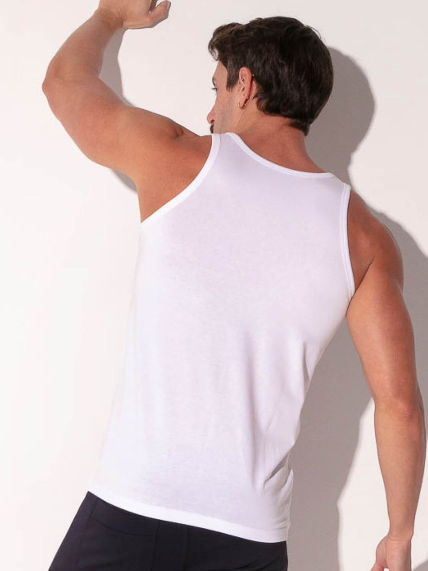 Man wearing a white tank top against a plain background