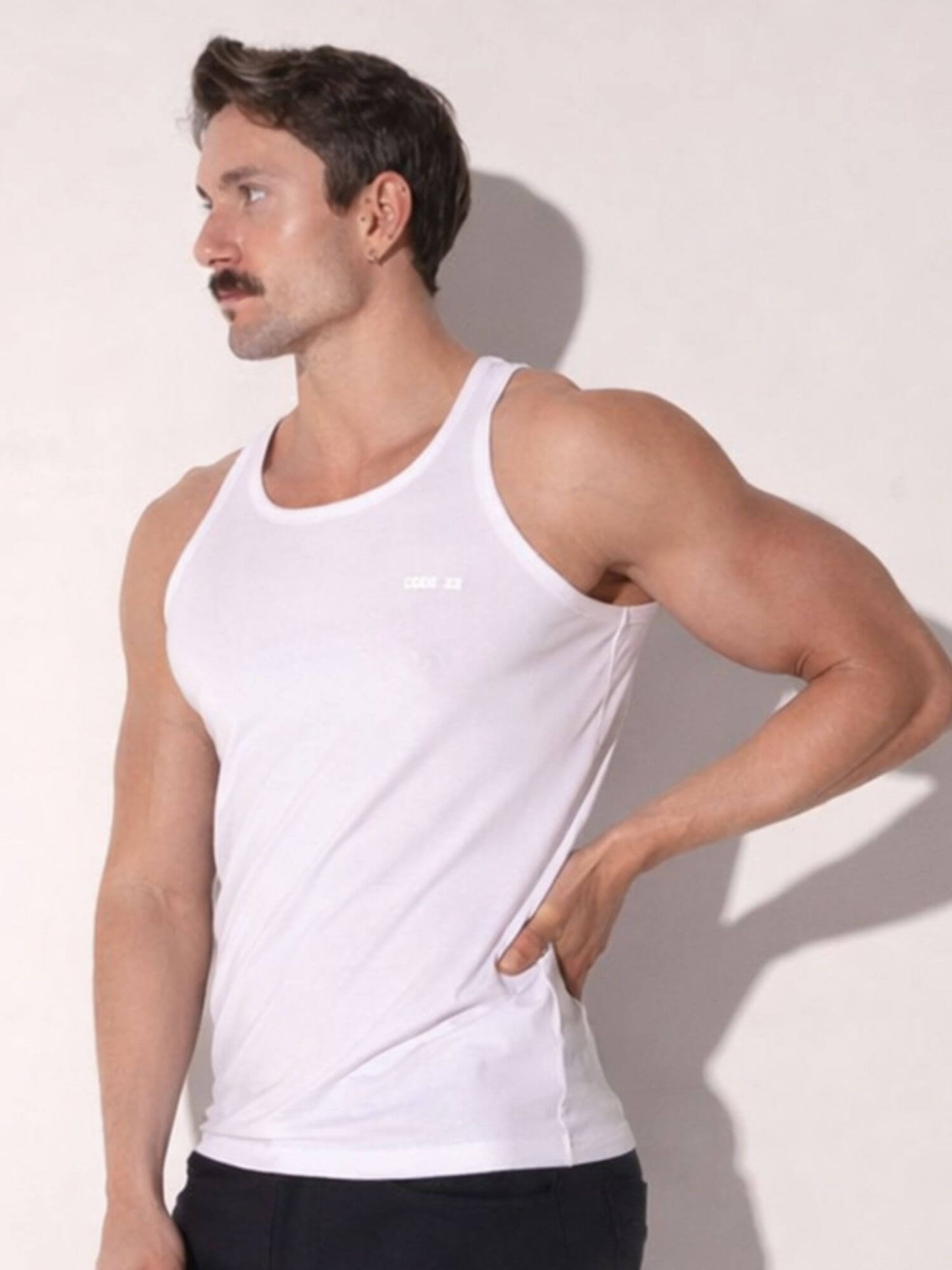 Man wearing a white tank top against a light background