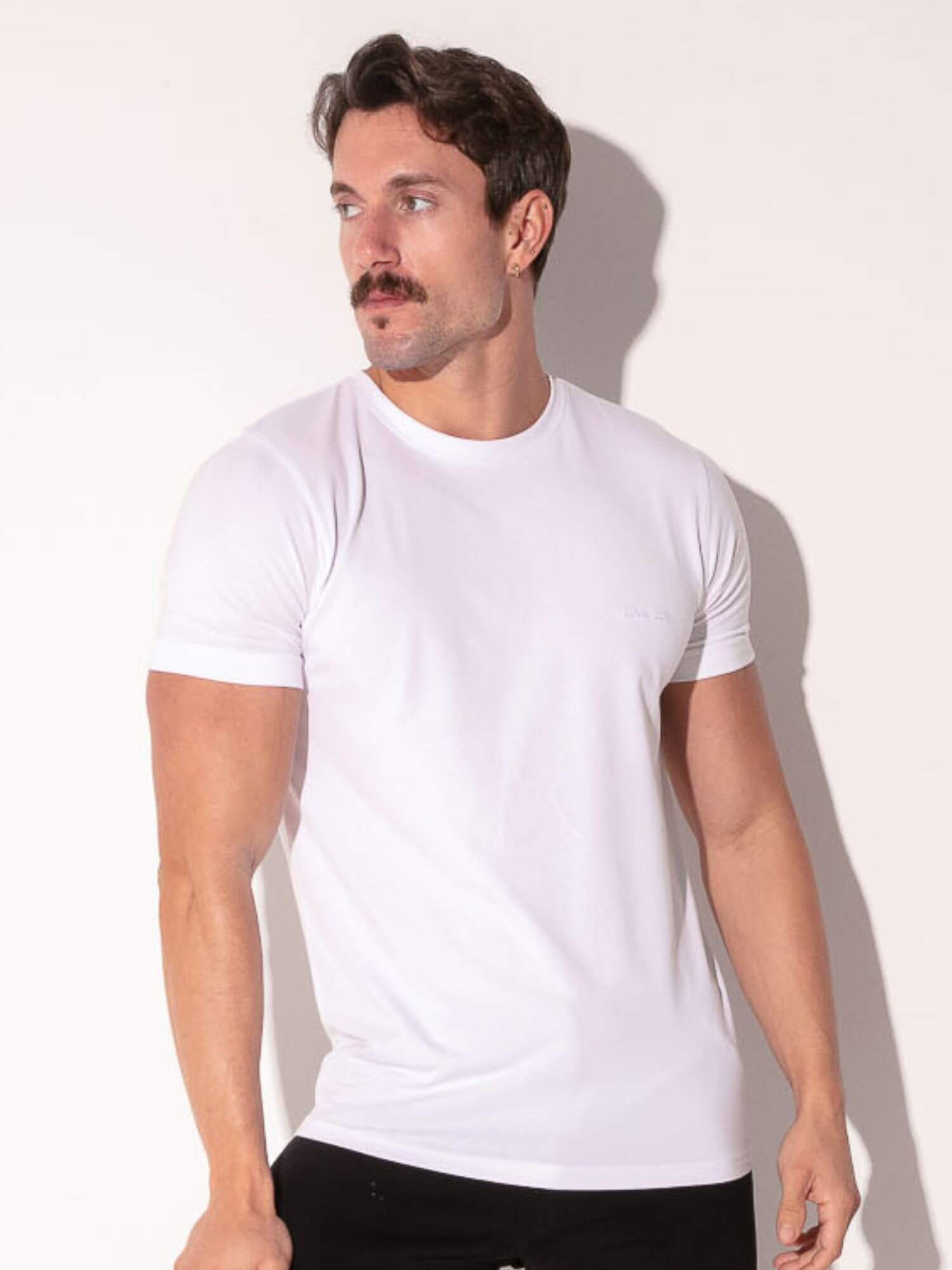 Man wearing a plain white t-shirt against a light background