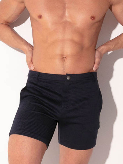 Man wearing navy blue shorts against a neutral background
