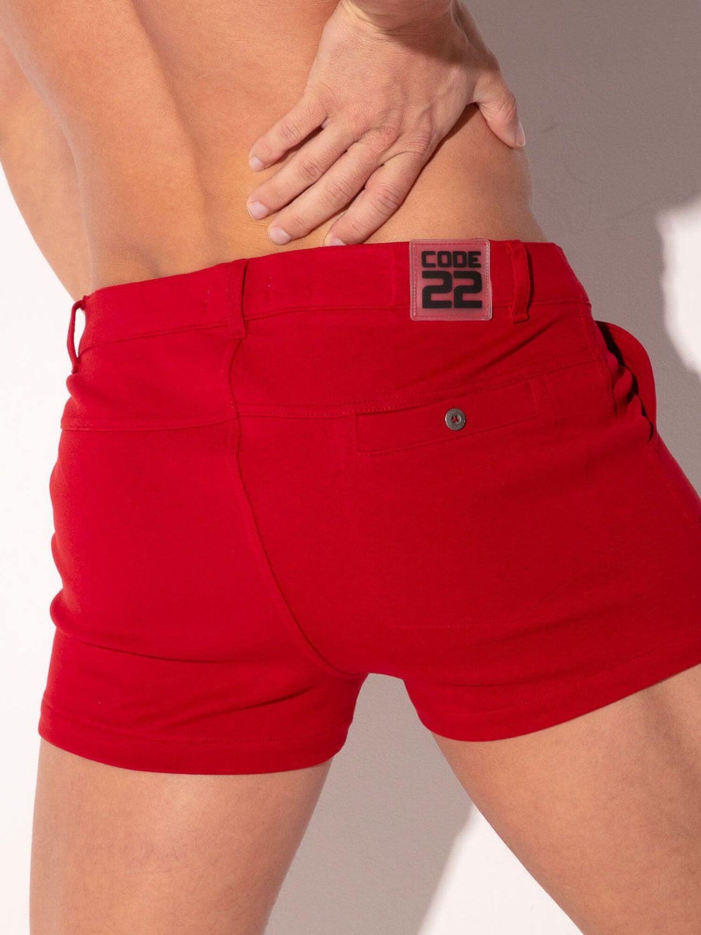 Red shorts with a brand logo on the back pocket against a neutral background