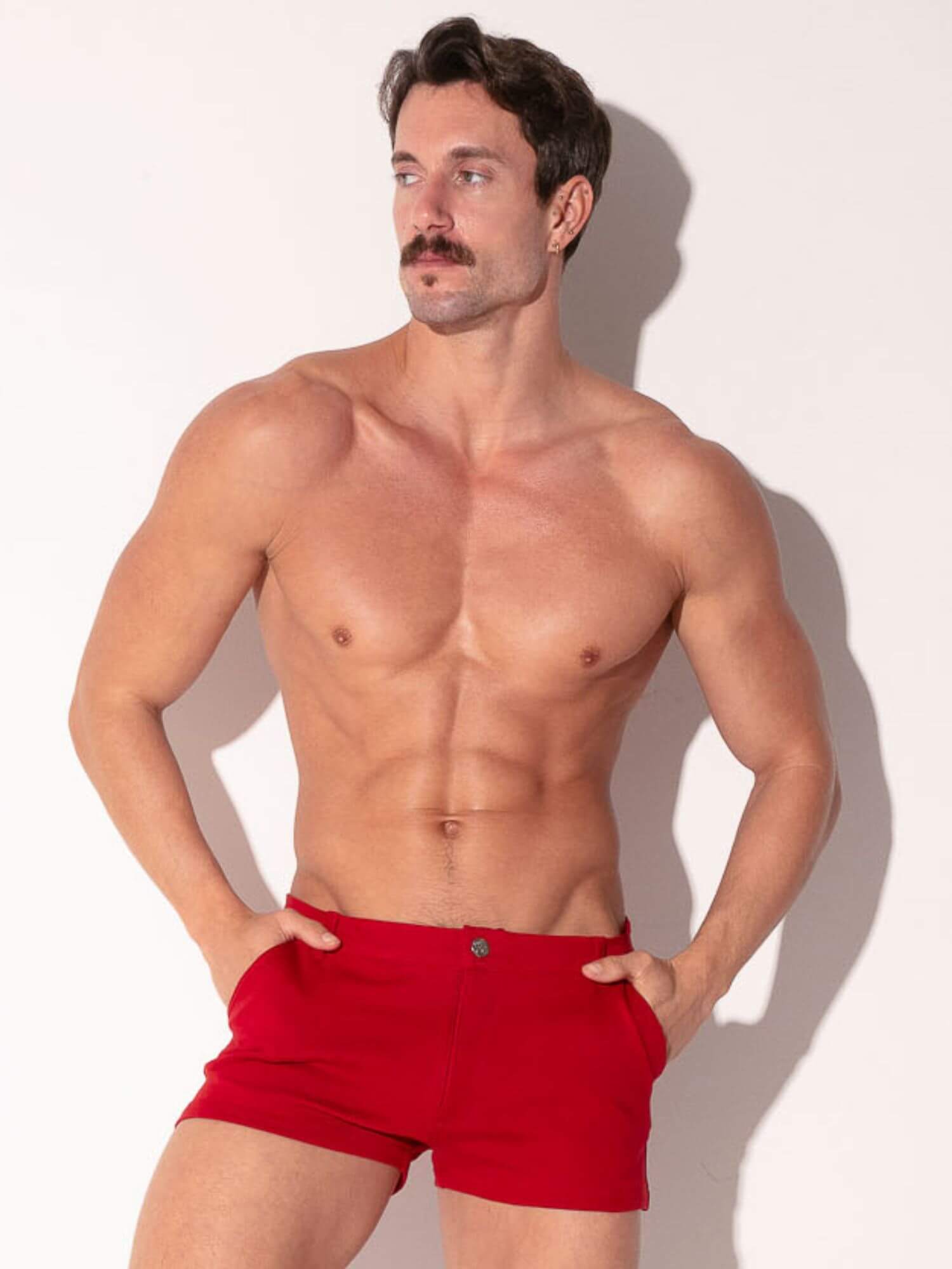 Man wearing red mini shorts against a white background