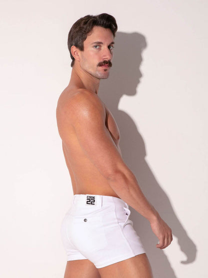Man wearing white cotton mini shorts with a brand logo on a plain background