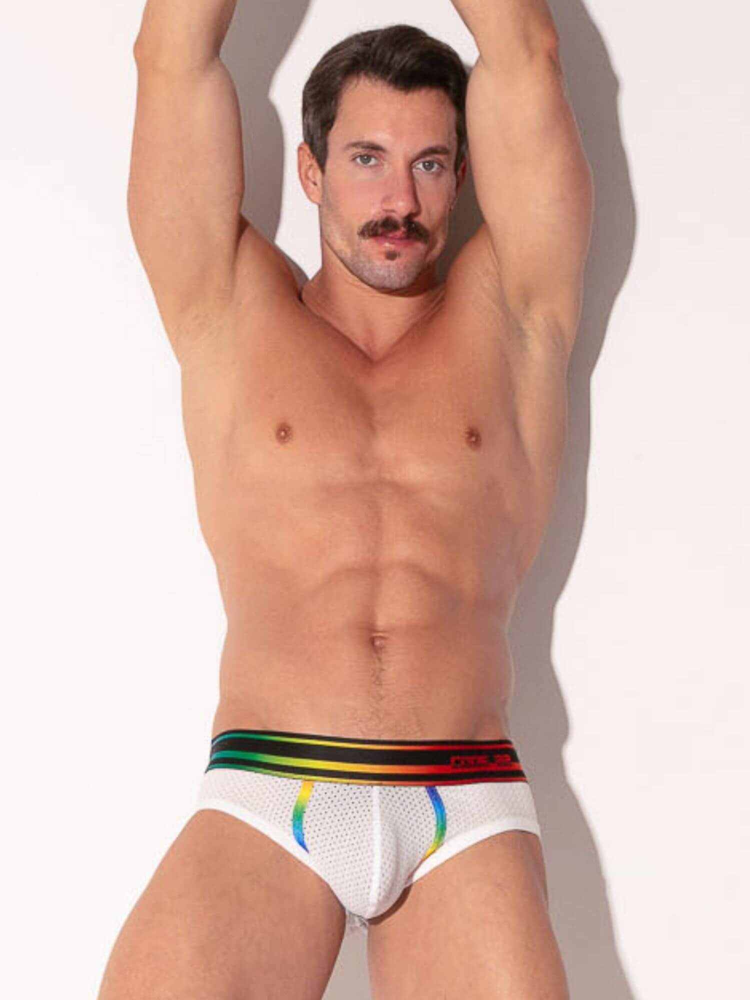 Man wearing a white underwear with rainbow trim on a plain background