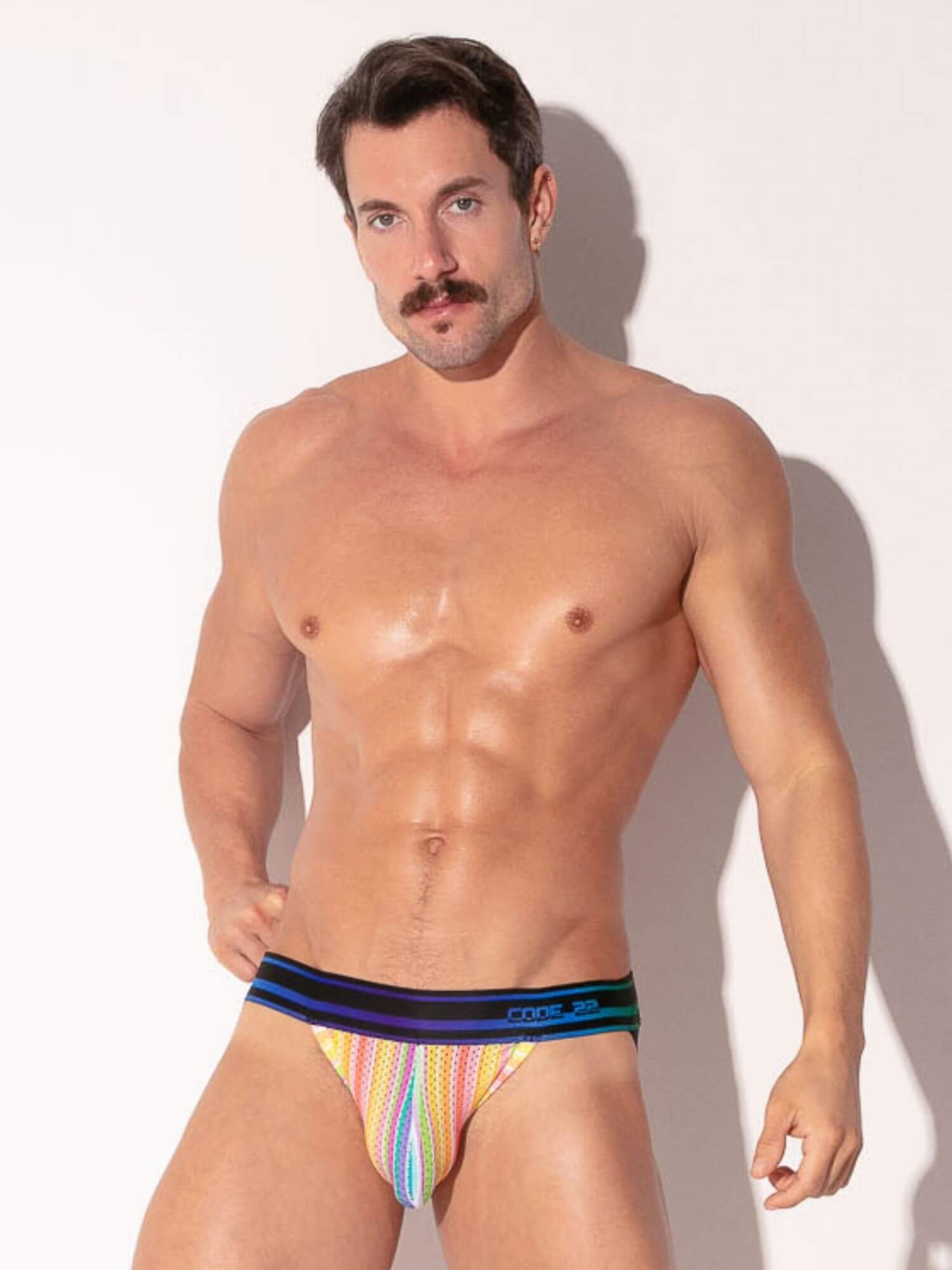 Man wearing colorful striped underwear against a plain background
