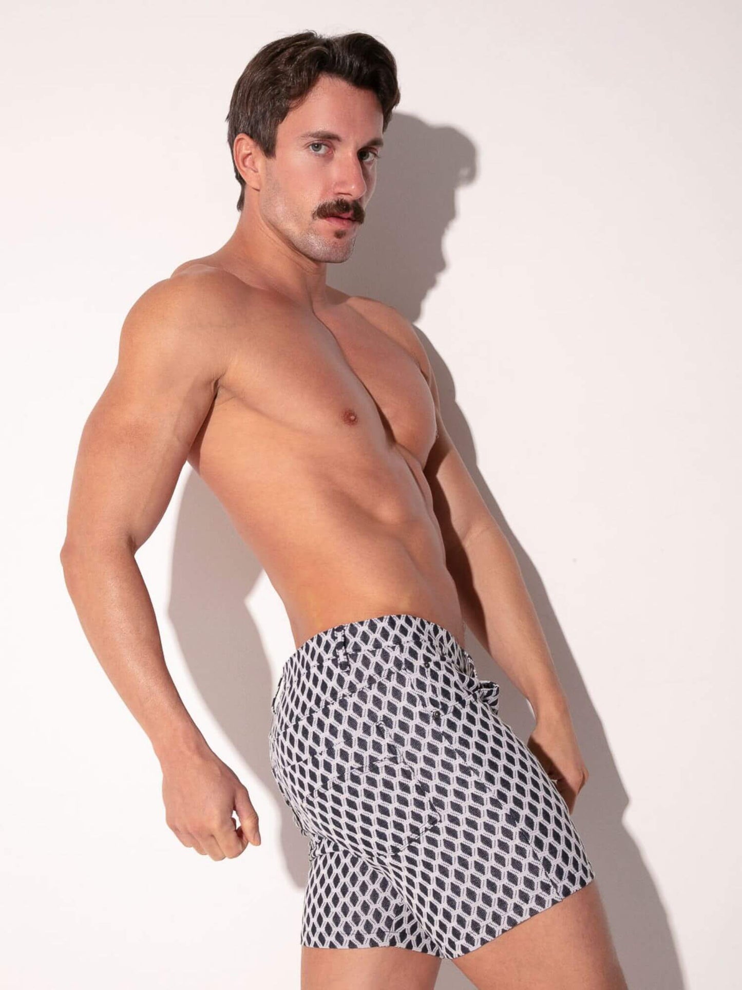 Man wearing patterned shorts against a plain background