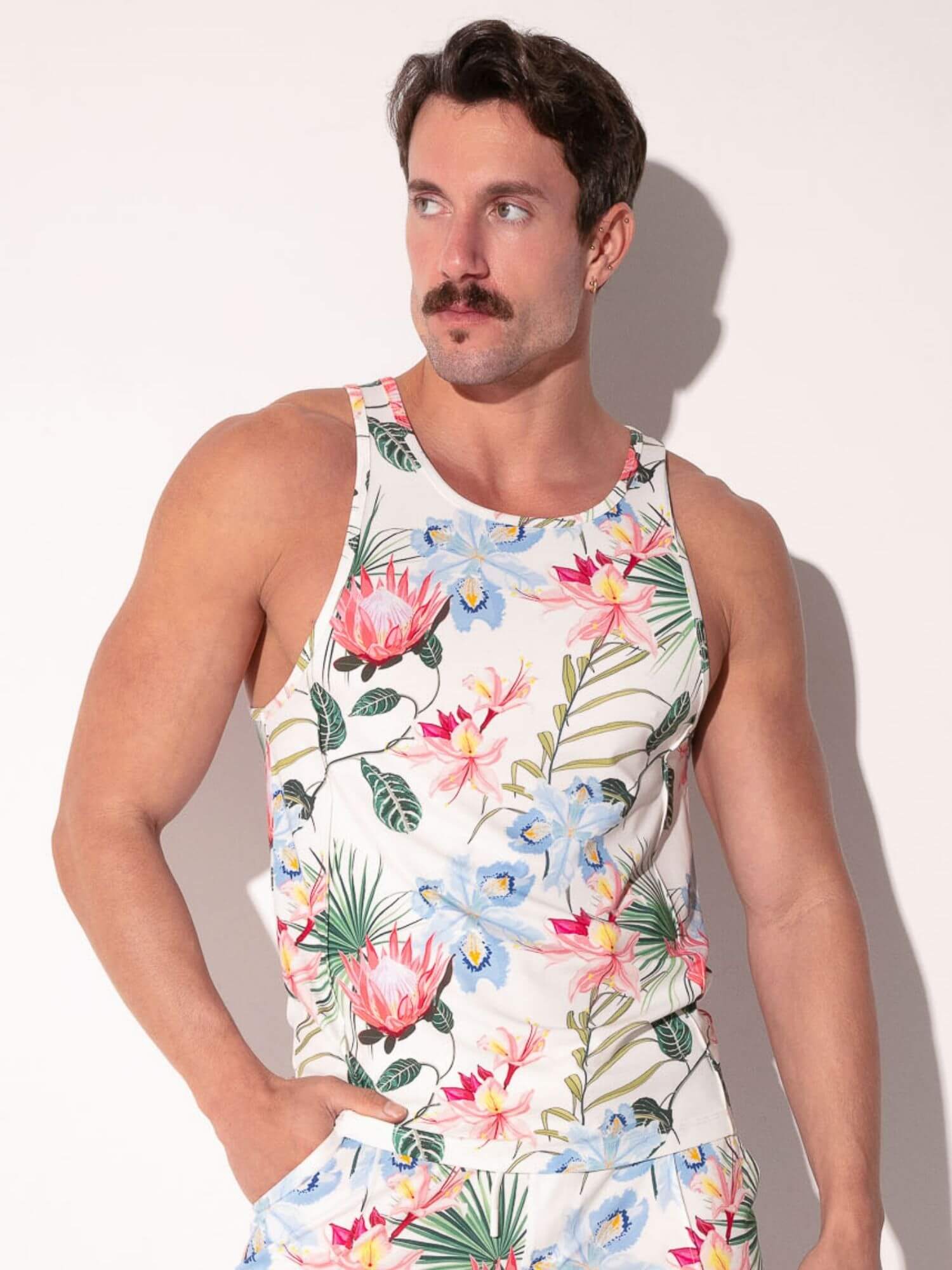 Man wearing a colorful floral tank top against a plain background