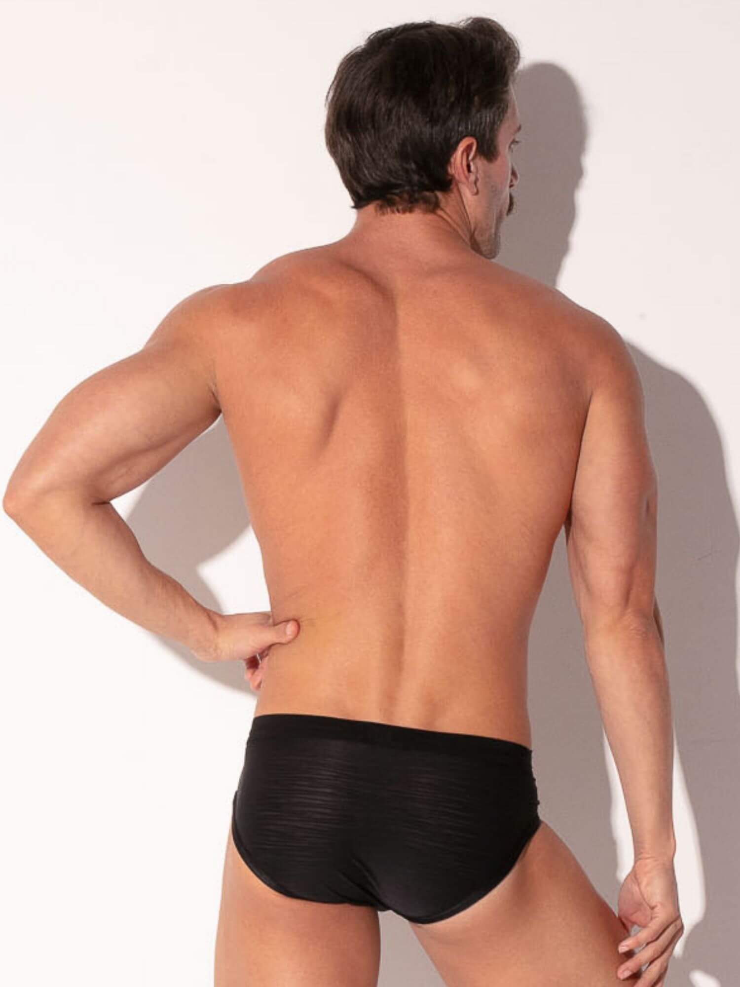 Man wearing black underwear against a white background
