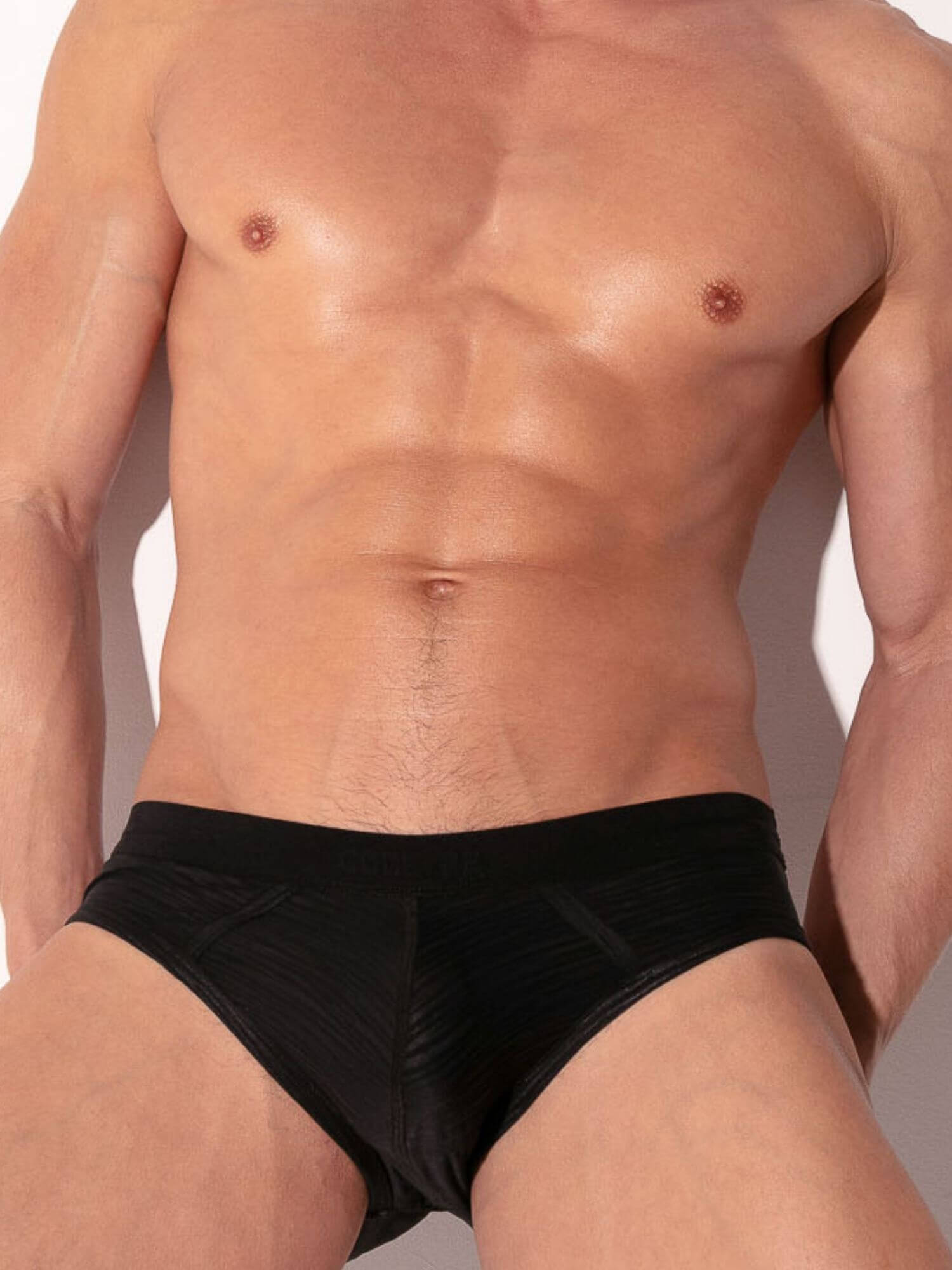 Man wearing black underwear against a neutral background