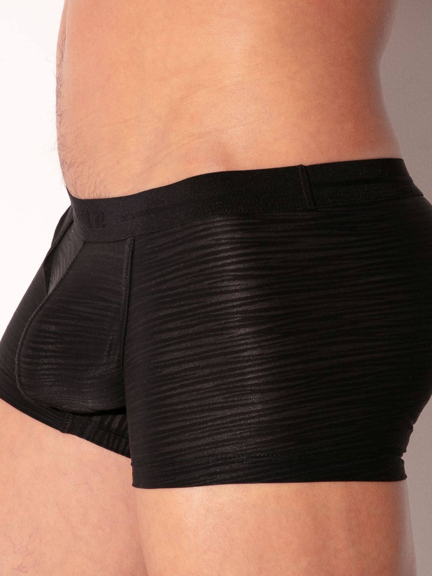 Black boxer briefs worn by a person on a plain background