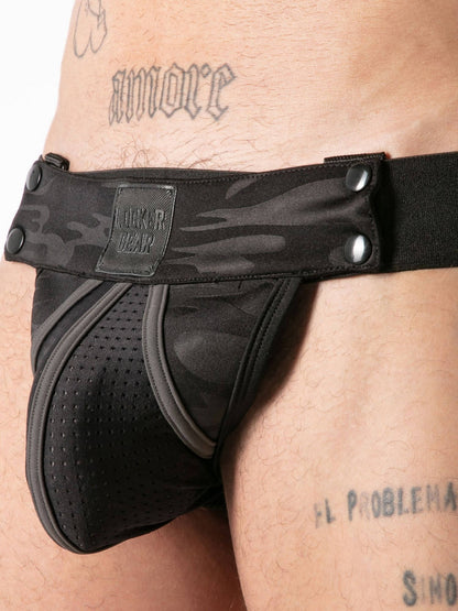 Black thong with camouflage pattern worn by a person, brand 'Locker Gear' visible.