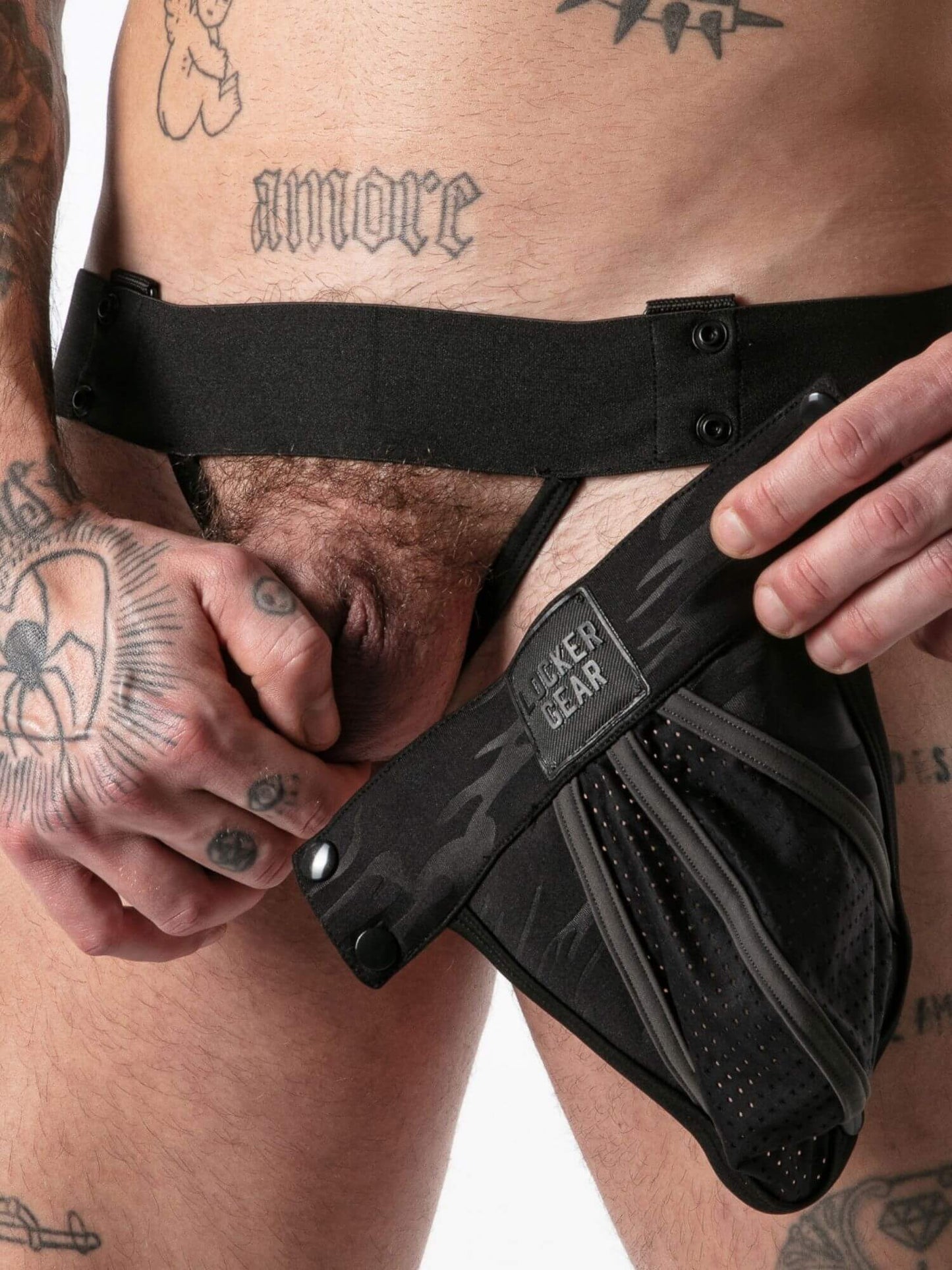 Person holding a black camo jockstrap with branding on a white background