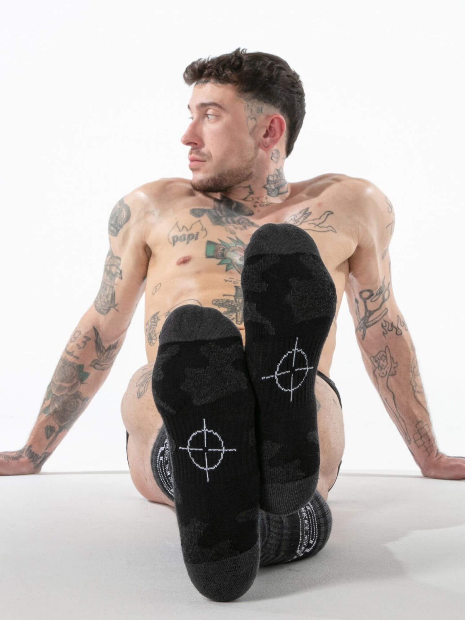 Man wearing black socks with white designs sitting on a white background