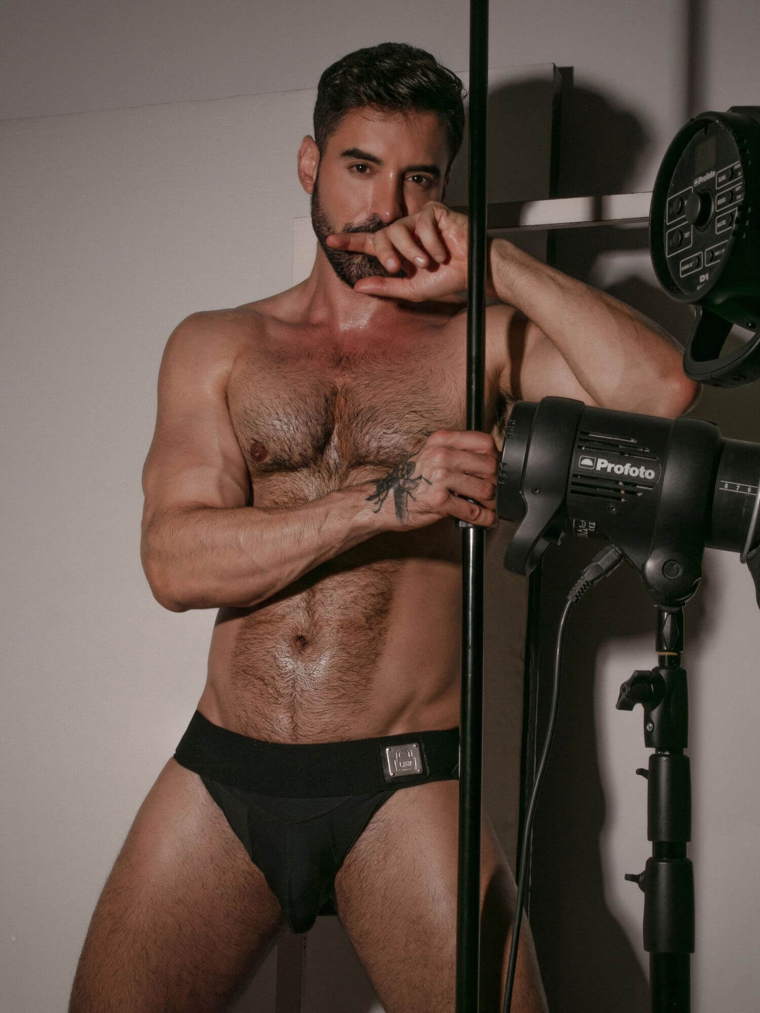 Man in black underwear posing with photography equipment in a studio setting