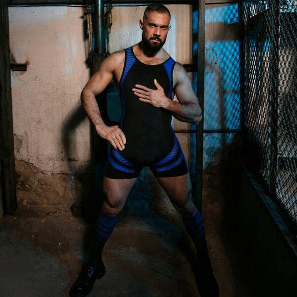 Man wearing a black and blue athletic outfit in a dimly lit room.