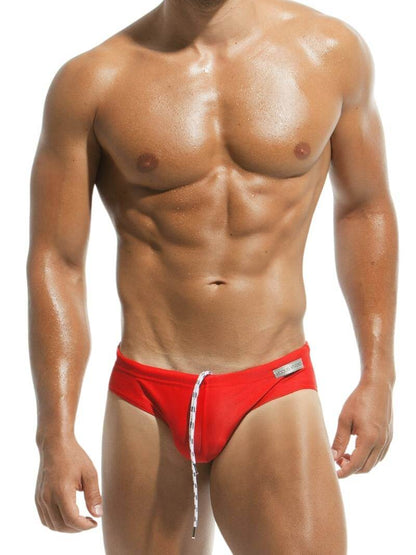A man wearing a red MODUS VIVENDI swimming brief with white drawstrings.