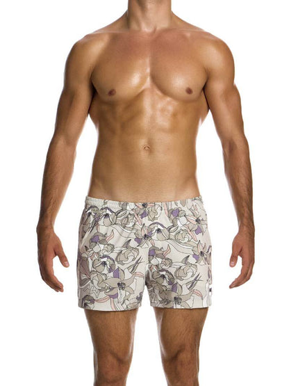 A man wearing art nouveau floral print swim shorts with elastic waistband and side pockets.