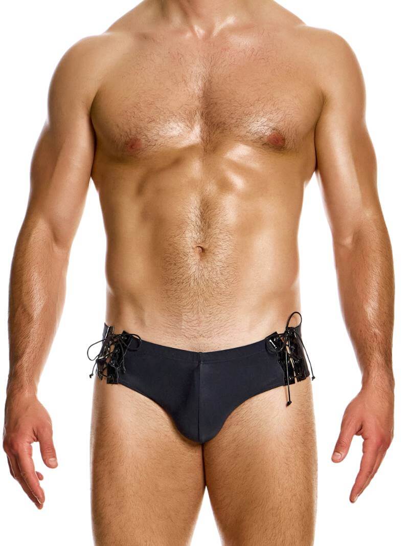 This image features the MODUS VIVENDI Boudoir Lace-Up Swimming Brief, modeled in smooth black fabric with shiny corset-style lace-up sides. The swim brief displays an adjustable lace-up tie string on high-shine glossy vinyl at the side panels, adding a distinctive and attractive detail to its design.