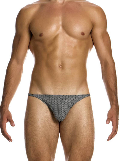 A male model wearing a Modus Vivendi Illusion Sheer Thong with a two-tone contrasting color intricate print in black/grey.
