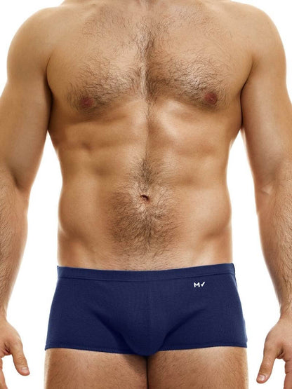 A model wearing blue Brazil-cut boxer underwear with a low-rise waistband and a small MV logo below the waistband.