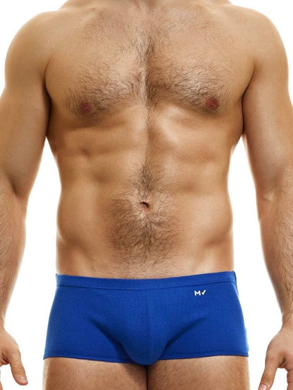 A model wearing blue Brazil-cut boxer underwear with a low-rise waistband and a small MV logo below the waistband.