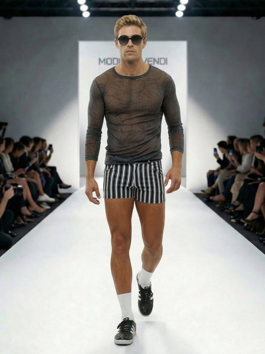 Man walking on a runway wearing a brown long-sleeve shirt and striped shorts, with 'Moda Operandi' branding in the background.