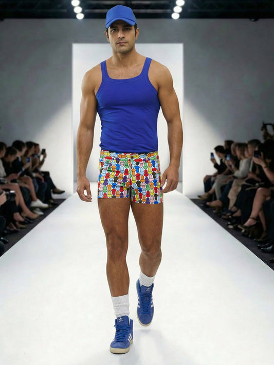 Model walking on a runway wearing a blue tank top, colorful shorts, and blue shoes.