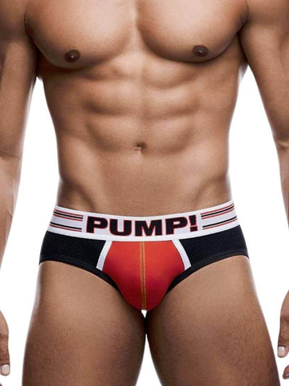 A model wearing a red and black PUMP Circuit jockstrap with contrasting white and black piping and a striped waistband.