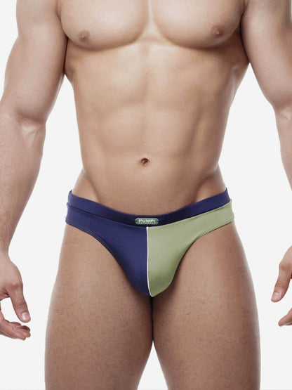Man wearing a blue and green swim thong on a white background