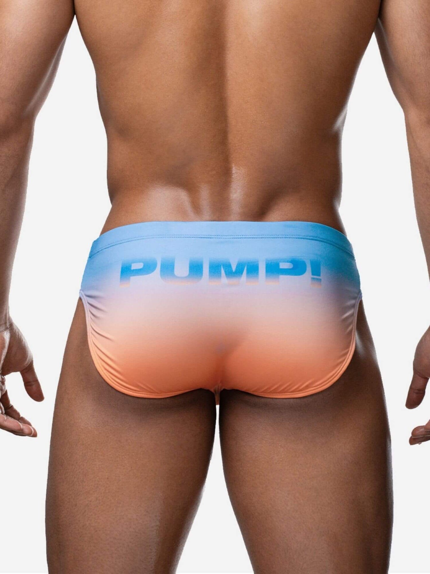 Man wearing a colorful swim brief with 'Pump!' branding on a plain background