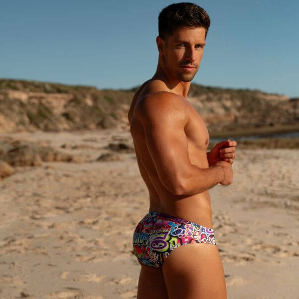 Man wearing colorful swim trunks on a beach