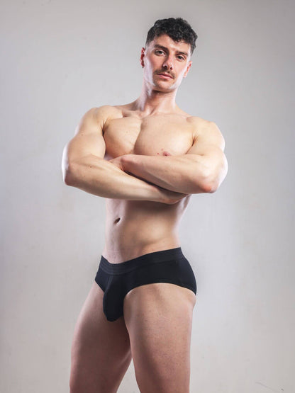 Man wearing a black underwear against a plain background