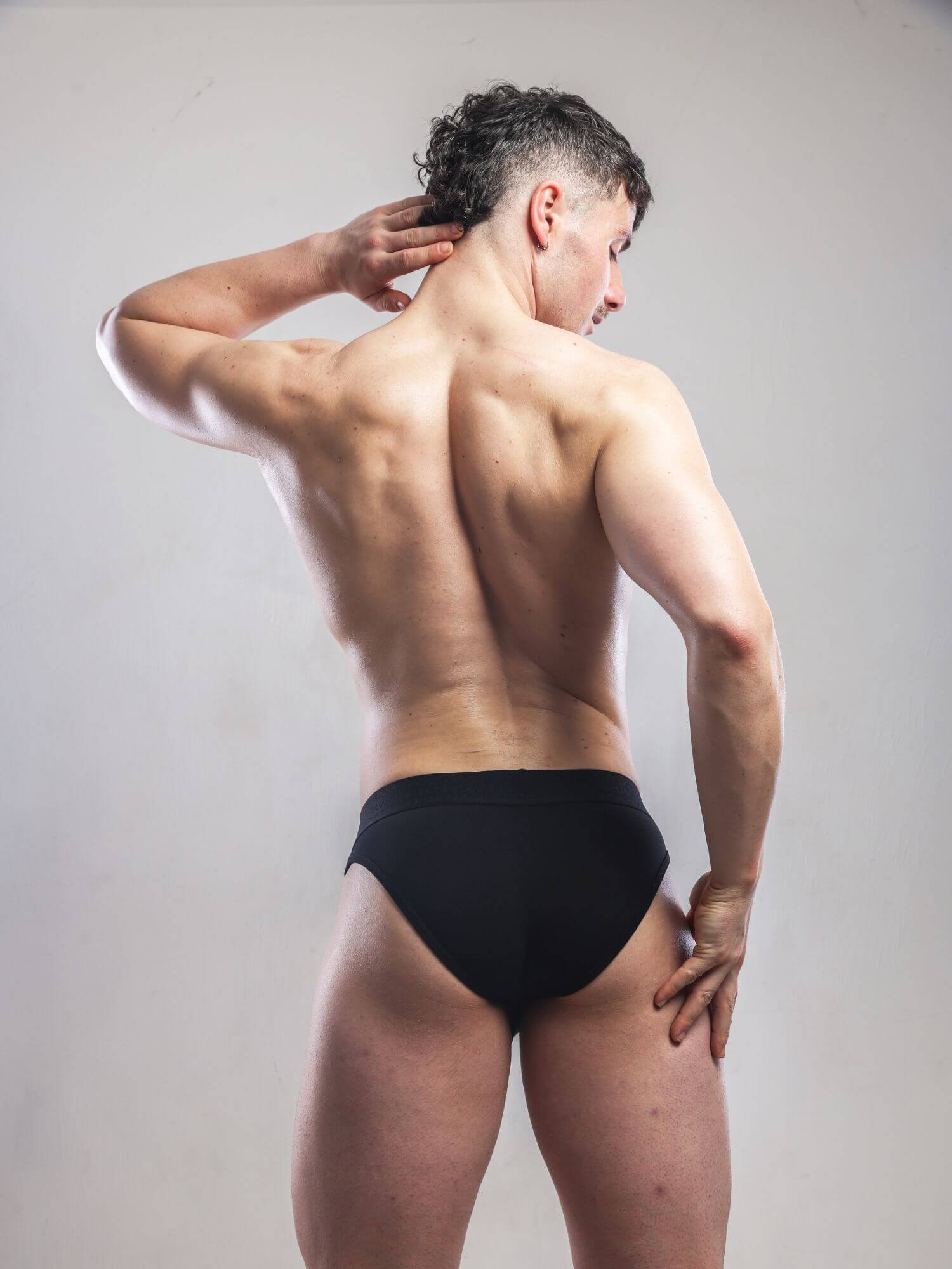 Man wearing black underwear against a plain background