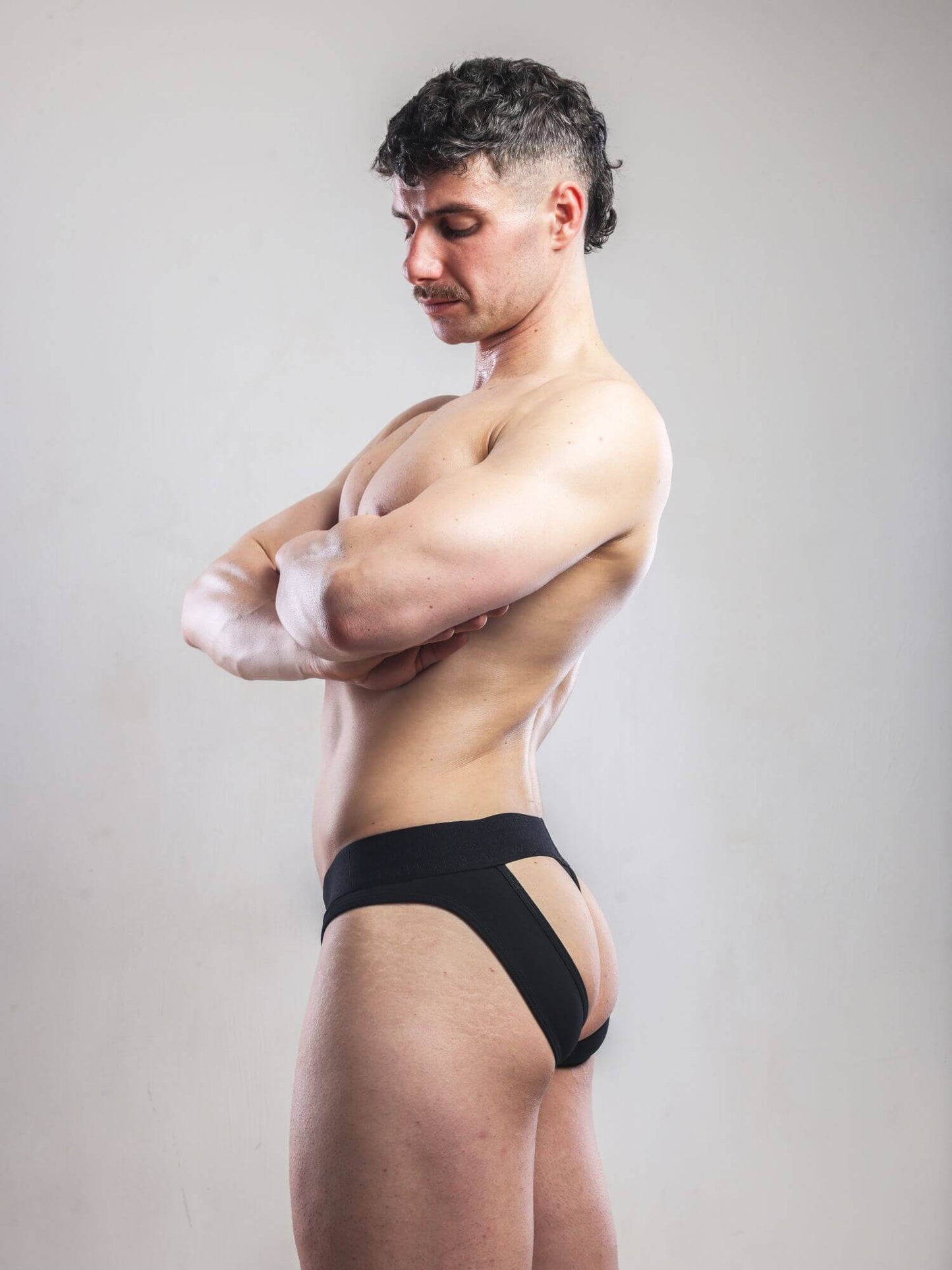 Man wearing black underwear against a plain background