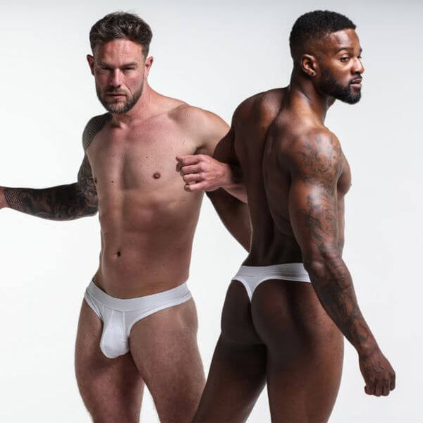 Two men wearing white underwear against a plain background