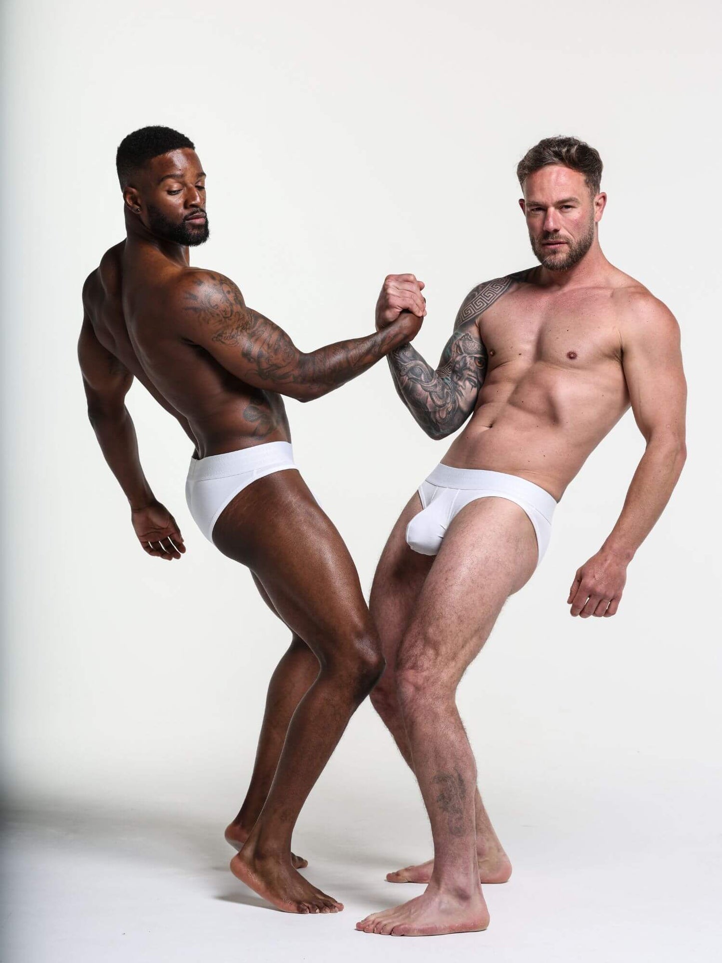 Two men wearing white underwear standing against a plain background