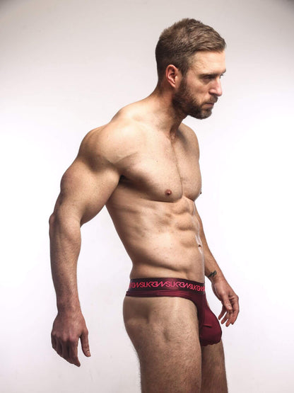 Man wearing a claret thong underwear with brand logo on a white background