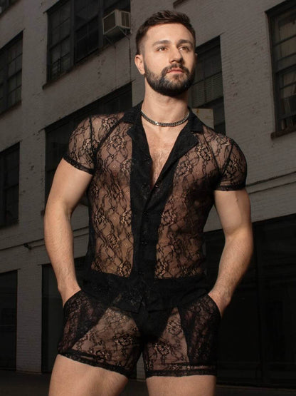 Man wearing a sheer black outfit with a building in the background