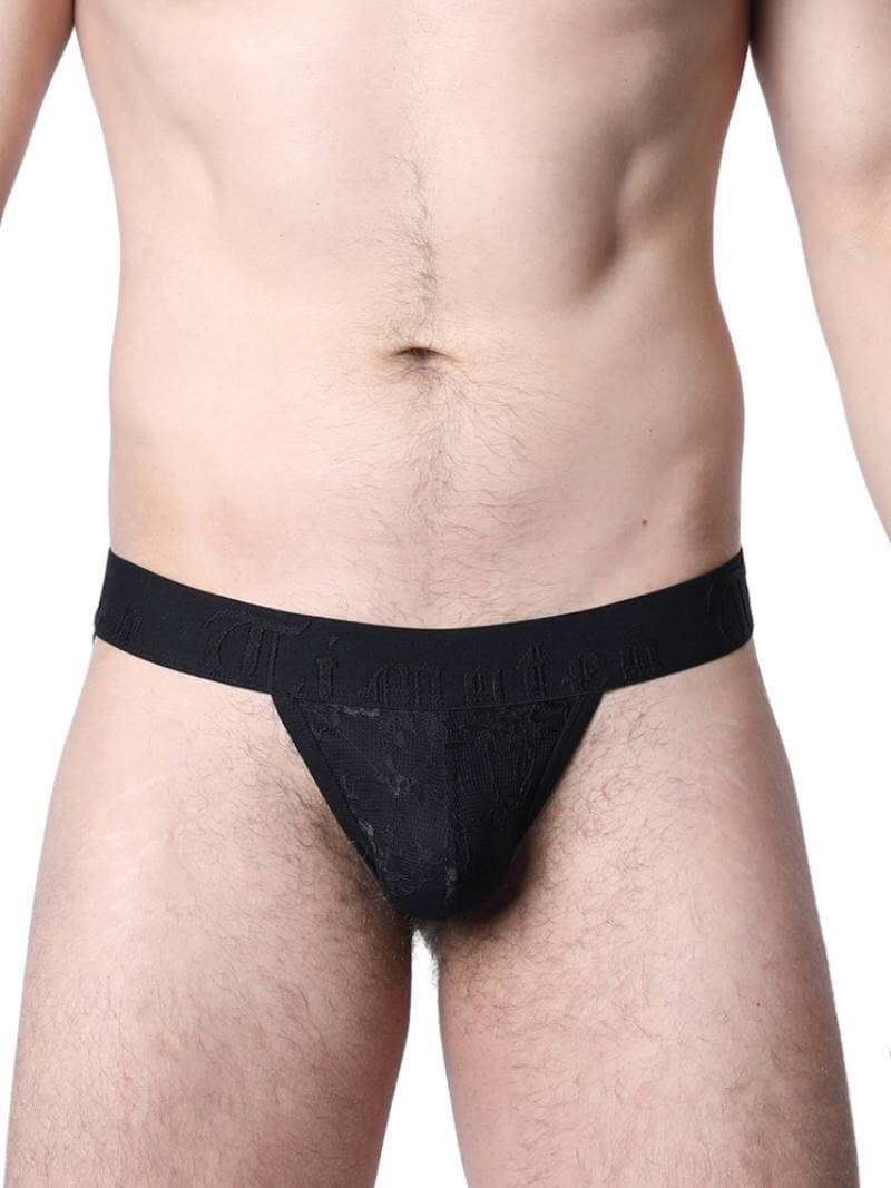 Man wearing black lace underwear standing in an urban setting.