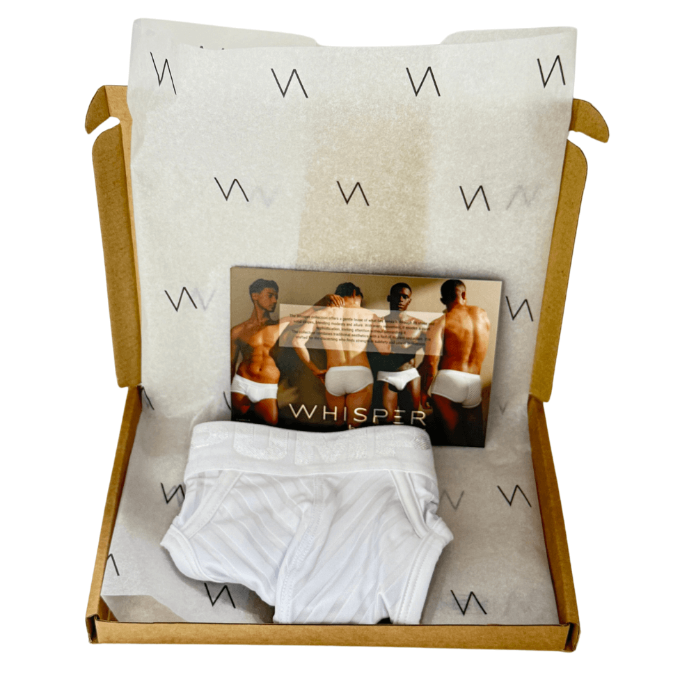 White boxer briefs and a magazine titled 'Whisper' in a box with branded interior.