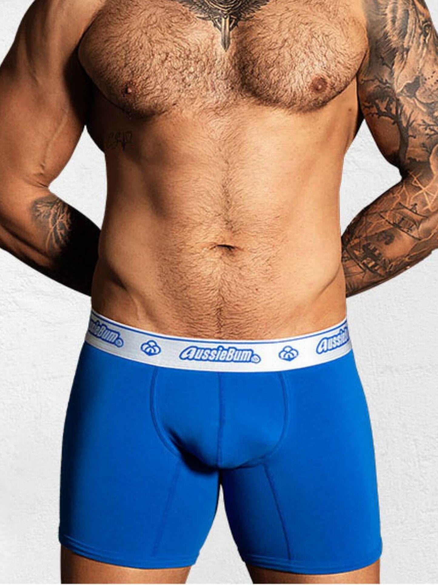 Person wearing blue boxer briefs with a visible brand logo on a plain background