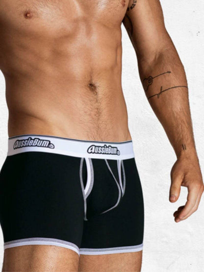 Person wearing black underwear with white waistband featuring 'AussieBum' brand on a plain background.